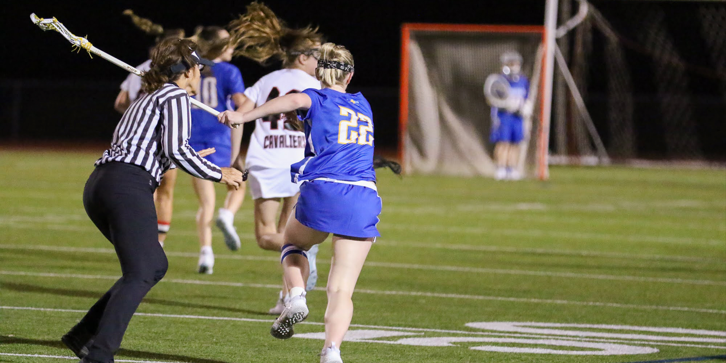 photo of a lacrosse official in the trail position running and following play towards the goal